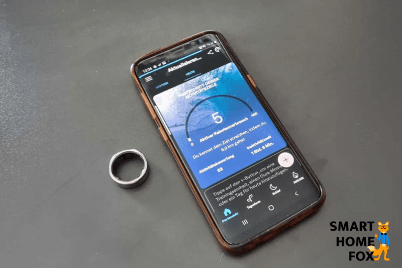 Oura Ring liegt neben der Handy-App auf dem Tisch